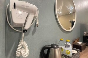 A hair dryer mounted on a wall, a kettle, and a mirror. - The S Design Hotel (Buriram City)