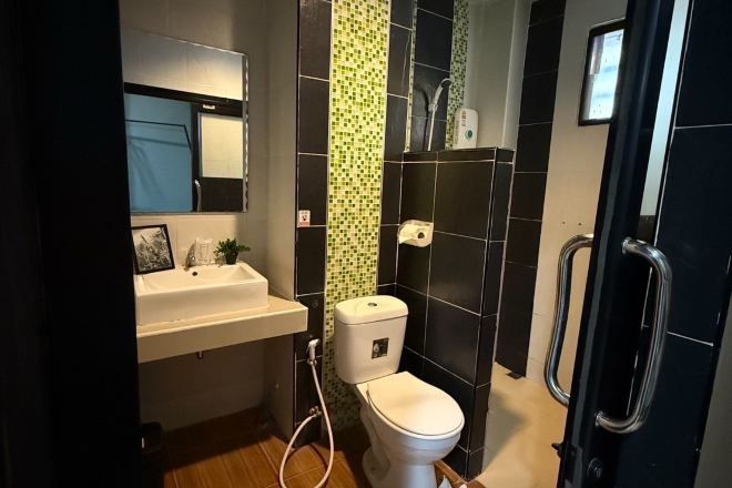 Un baño pequeño con inodoro blanco, lavamanos y zona de ducha.