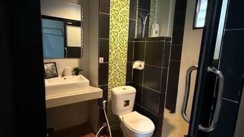 Un baño pequeño con inodoro blanco, lavamanos y zona de ducha.