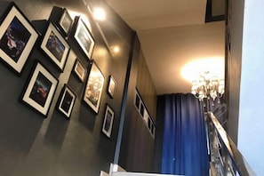 Un escalier orné d’un lustre et de tableaux encadrés accrochés au mur.