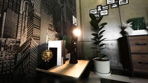 Un bureau avec une plante en pot, un globe terrestre et des photos encadrées accrochées au mur.