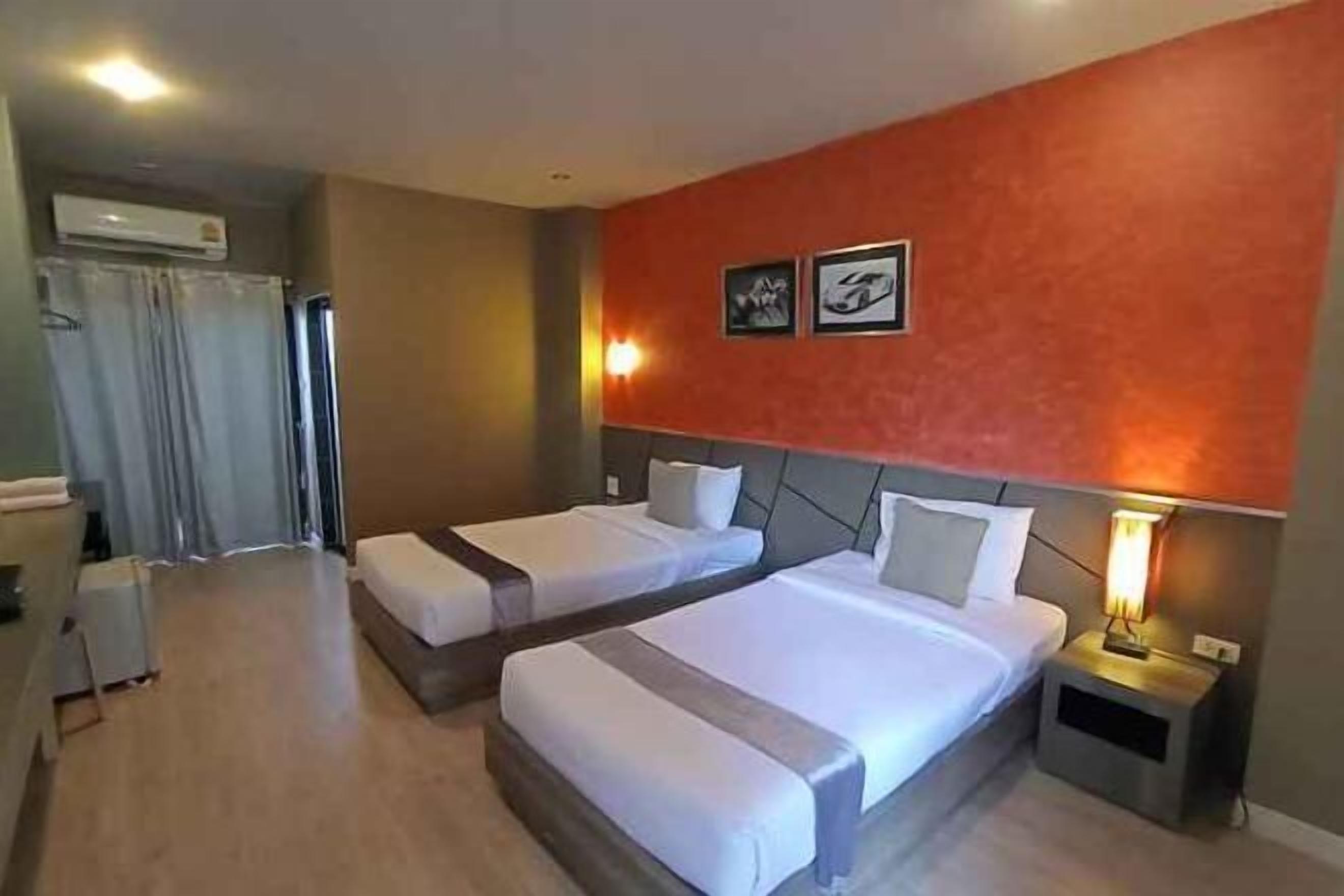 Une chambre d’hôtel avec deux lits, une table de chevet avec une lampe, un appareil de climatisation et un espace douche.
