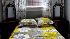 Une chambre à coucher avec un lit, des rideaux et une fenêtre équipée de stores.