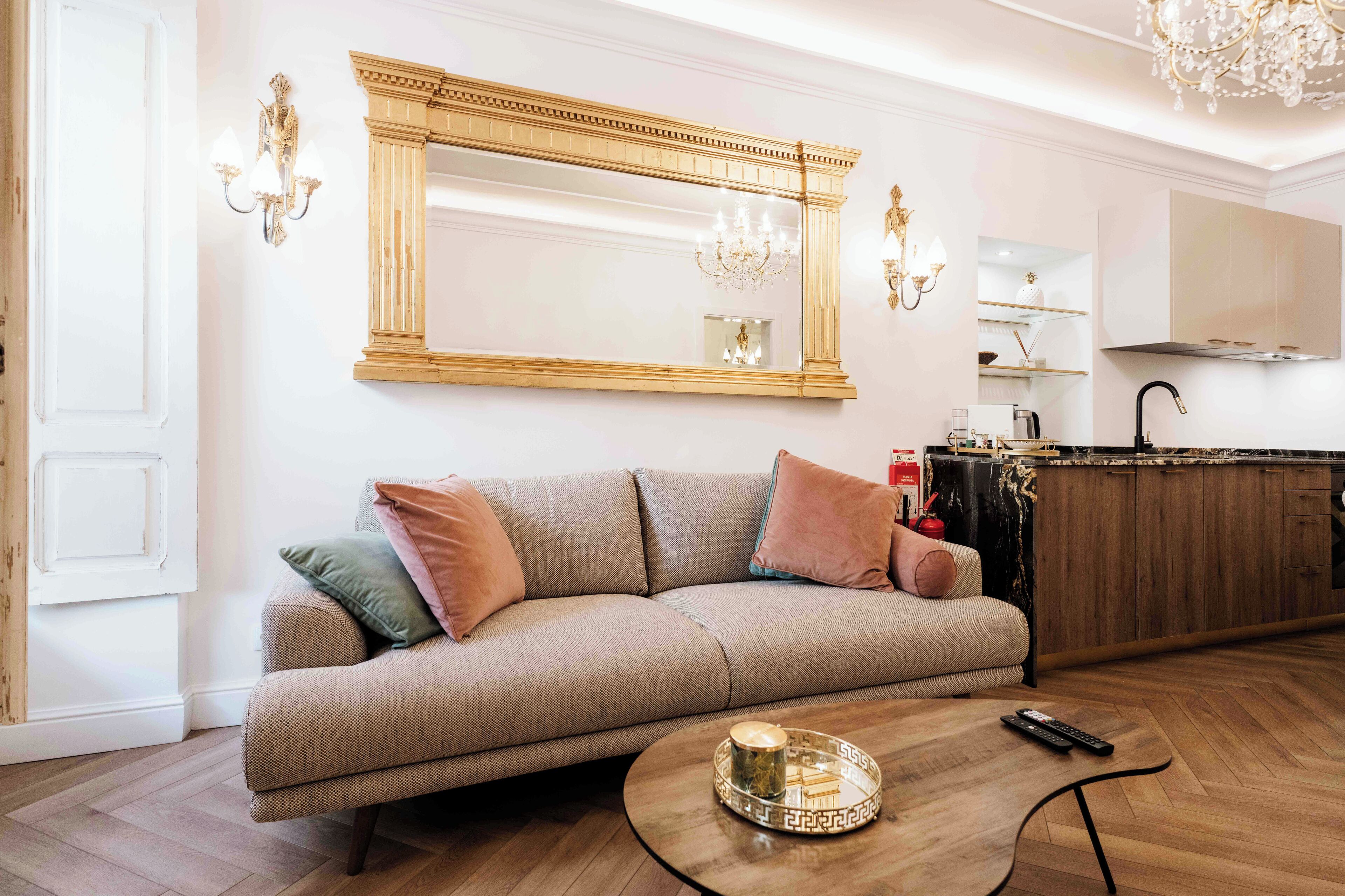 Una sala de estar moderna con un sofá beige, una mesa de centro redonda y un espejo grande.