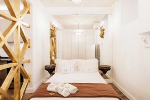 Ein Hotelzimmer mit einem großen Bett, einer Wand mit Holzverkleidung, einer Kronleuchter und einem Spiegel.
