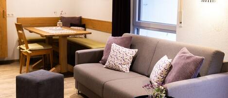 A modern living room with a sofa, a dining table, and a small side table with a vase.