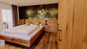 A bedroom with a wooden bed, a nightstand, and a wall-mounted lamp. - Schiebenrothenhof (Simonswald)