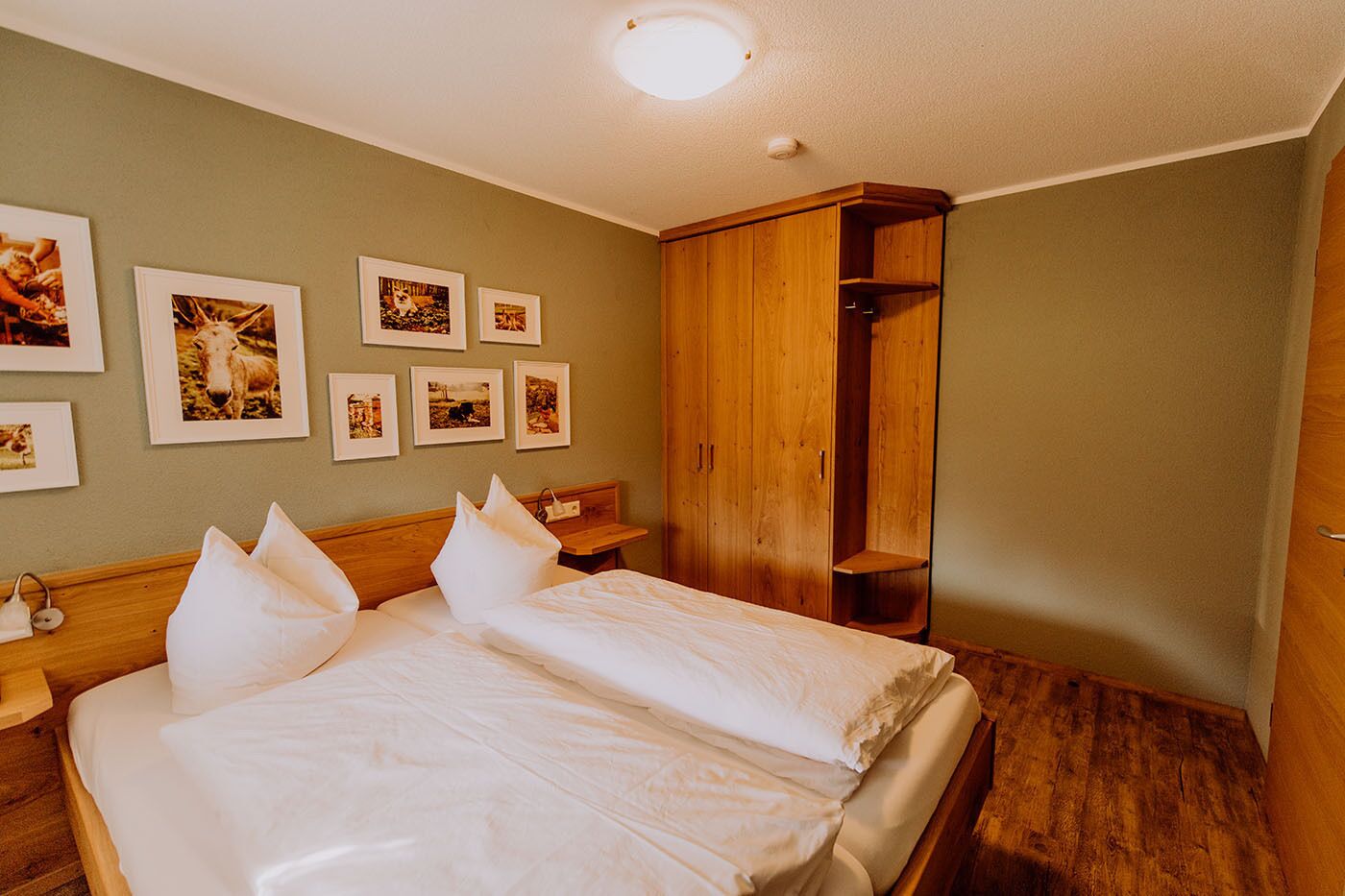 Ein Hotelzimmer mit einem Bett, einem Holzschrank und Bildern an der Wand.