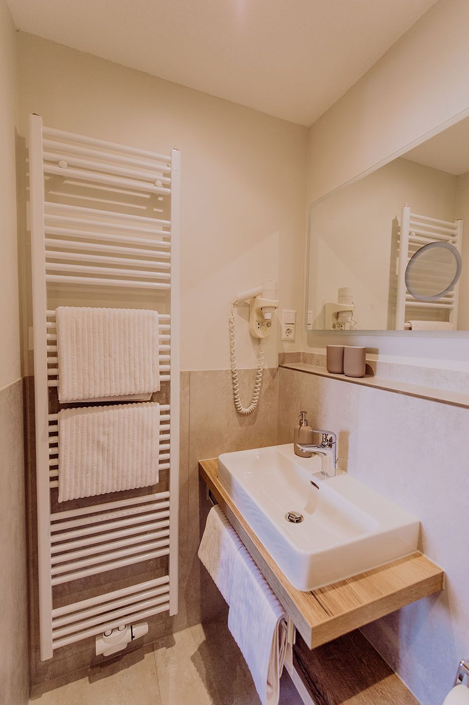 Un baño con toallero, lavamanos, espejo y ducha.