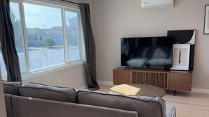 A modern living room with a grey sectional sofa, a flat-screen TV, and a wooden cabinet.