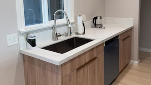 A modern kitchen with a double sink, wooden cabinets, and a window above the sink.
