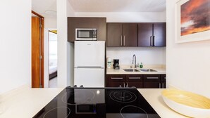 A compact kitchen with a microwave, refrigerator, stove, and sink. - Avila Suites (San Juan)