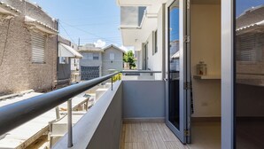 A narrow balcony with a metal railing, a sliding glass door, and a tiled floor. - Avila Suites (San Juan)