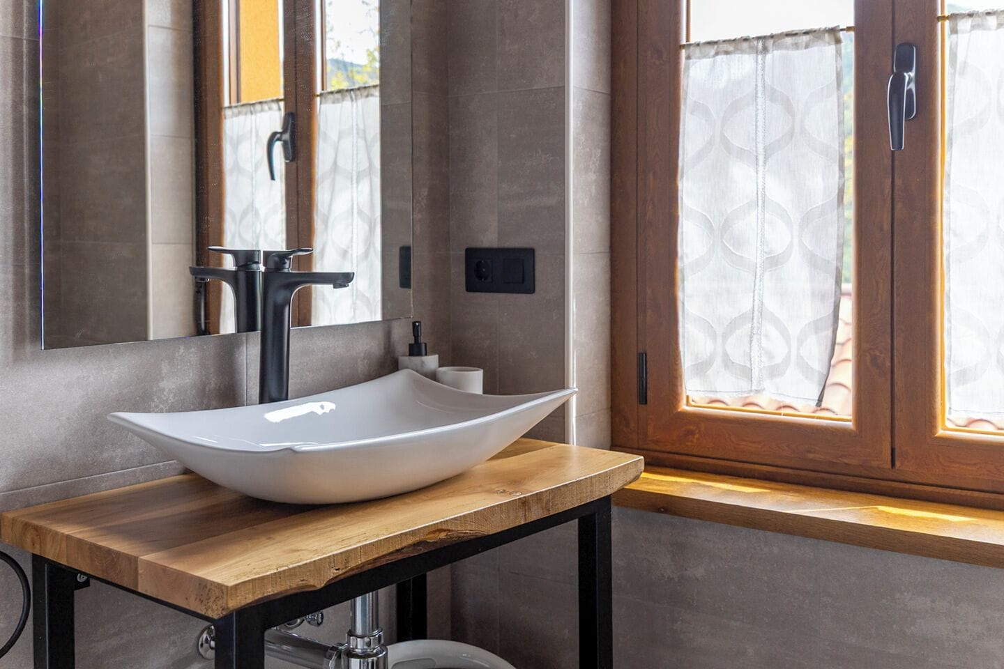 Un bagno moderno con un lavabo a incasso, un mobile vanità in legno, uno specchio e una finestra con tende.