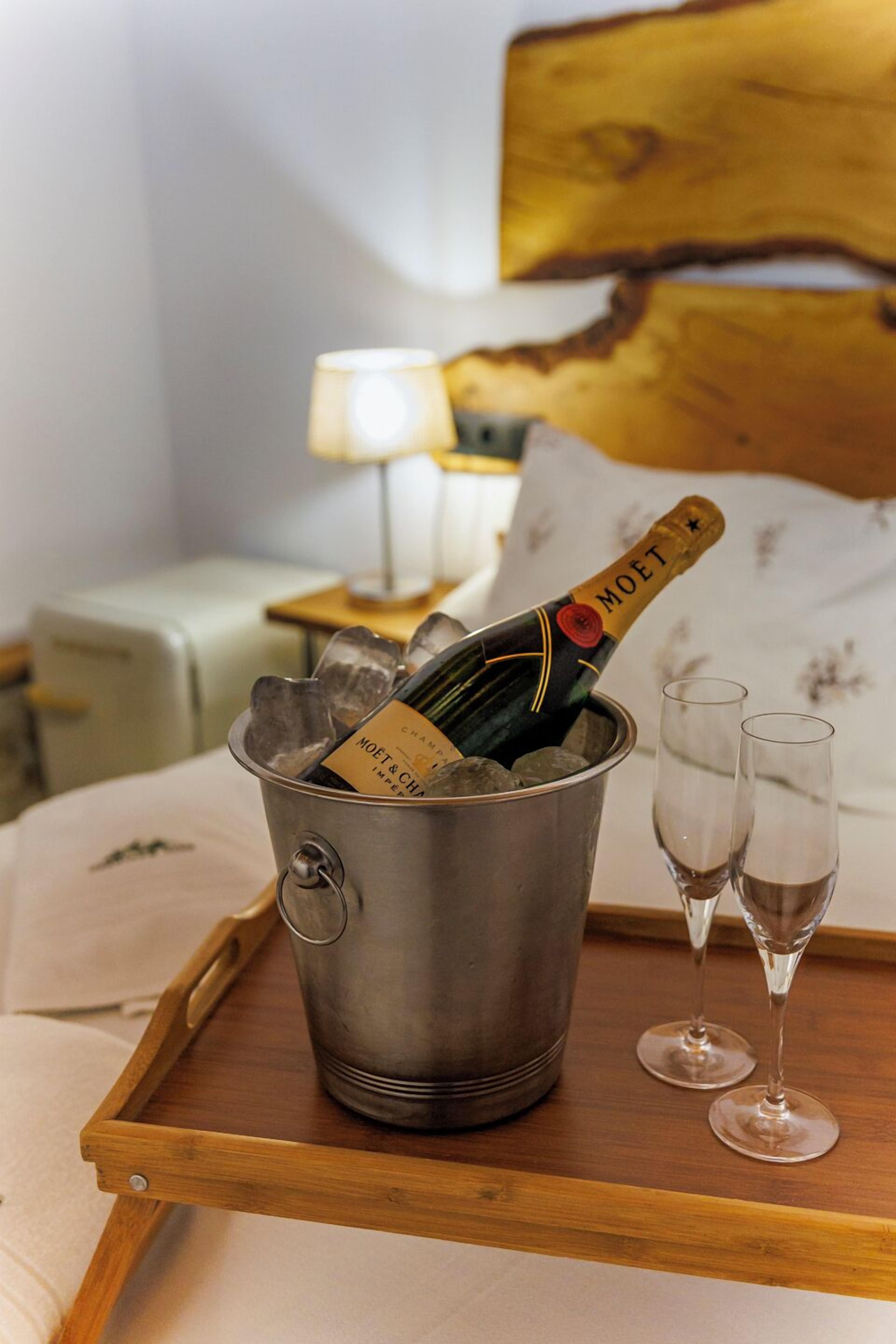 Un balde metálico con una botella de Moët champagne y dos copas sobre una bandeja de madera.