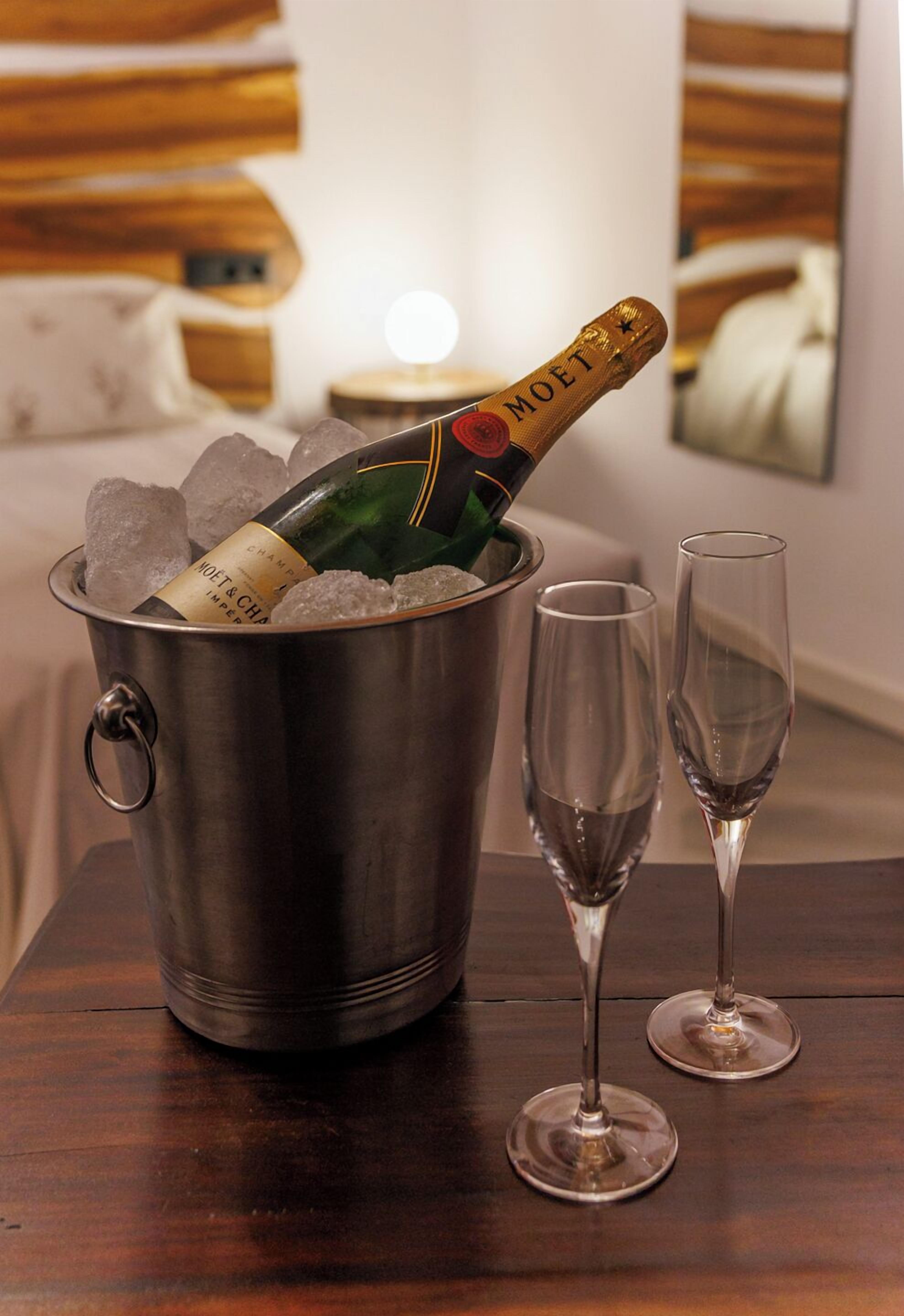Un mini bar con una botella de champán Moët, cubitos de hielo y dos copas de vino vacías sobre una mesa de madera.