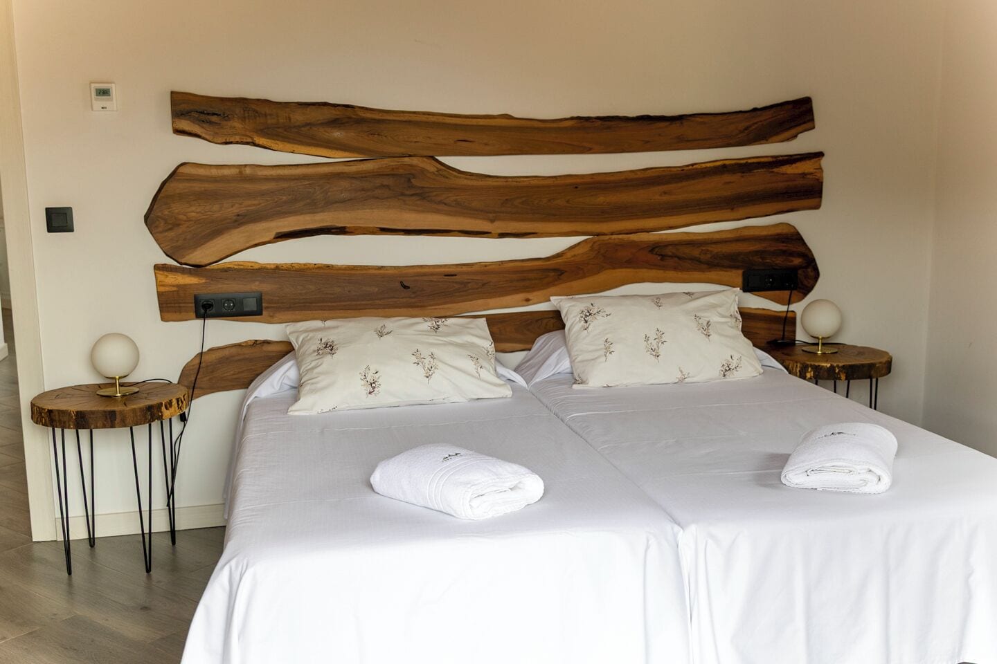 A double bed with a wooden headboard, two bedside tables with lamps, and floral-patterned pillows.
