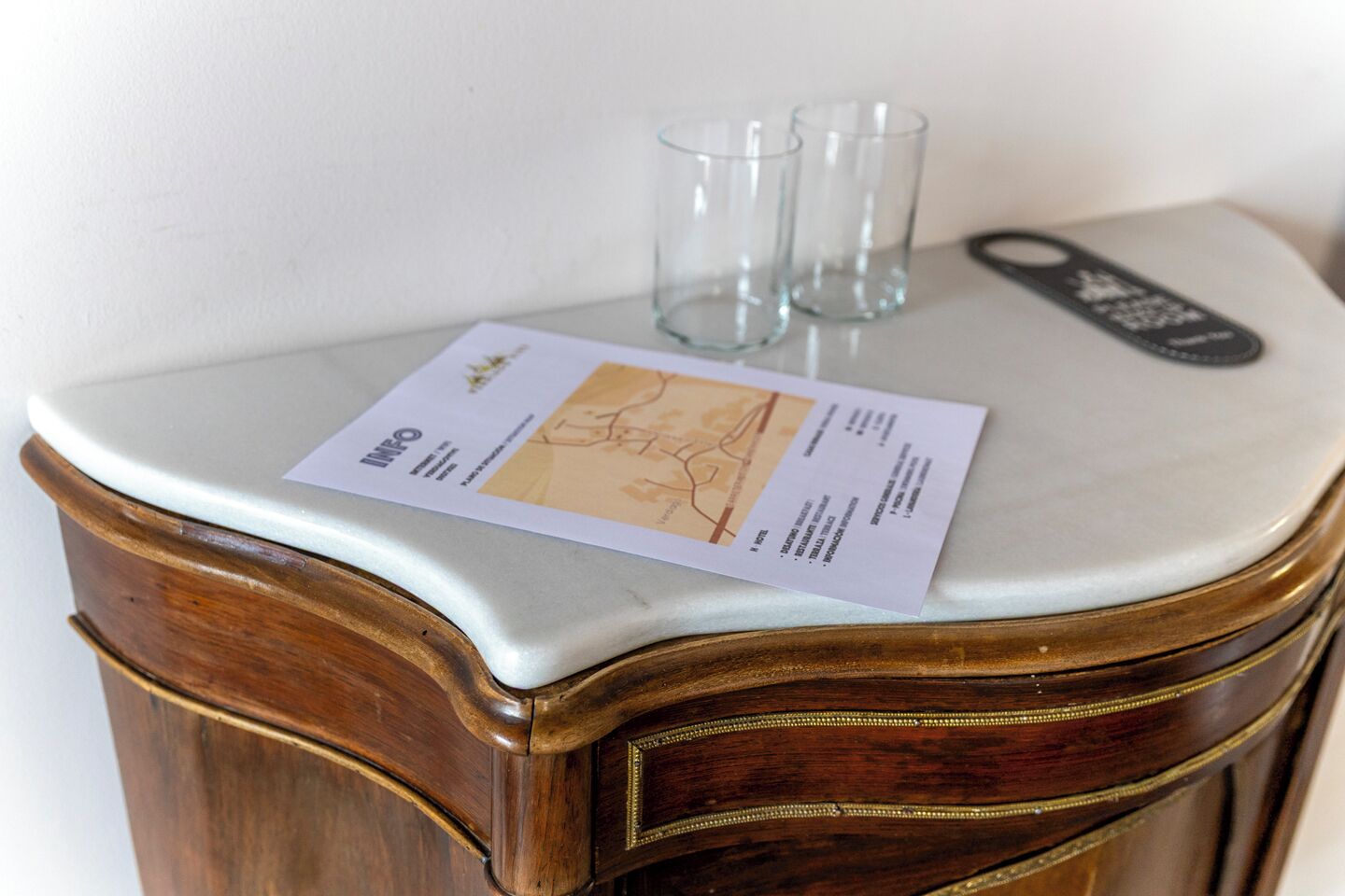 A wooden cabinet with a marble top, a map, and two empty glasses.