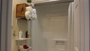 A bathroom with a bathtub, a toilet, a sink, and a shelf with toiletries. - The Trailway Hub, ideally located in Deer Lake, 10 minutes from the airport (Deer Lake)