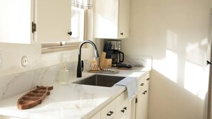Una cocina con encimera de mármol, un lavabo y una cafetera.