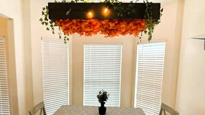 A dining area with a table set for four, surrounded by chairs, under a decorative ceiling with foliage and lights. - Charming 3-bedroom cottage in gorgeous Oxford  (Oxford)
