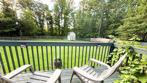 A wooden deck with two Adirondack chairs, a small shed, and a fenced yard with grass and trees. - Charming 3-bedroom cottage in gorgeous Oxford  (Oxford)