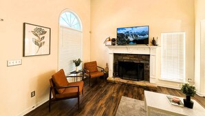 A living room with a fireplace, a television, and two chairs. - Charming 3-bedroom cottage in gorgeous Oxford  (Oxford)