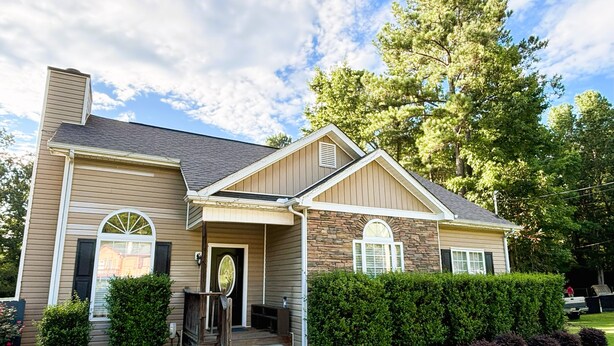 A two-story house with a stone facade, a front porch, and a well-maintained lawn. - Charming 3-bedroom cottage in gorgeous Oxford  (Oxford)