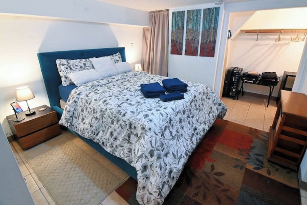 A bedroom with a bed, a nightstand, a desk, and a chair.