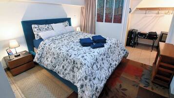A bedroom with a bed, a nightstand, a desk, and a chair.