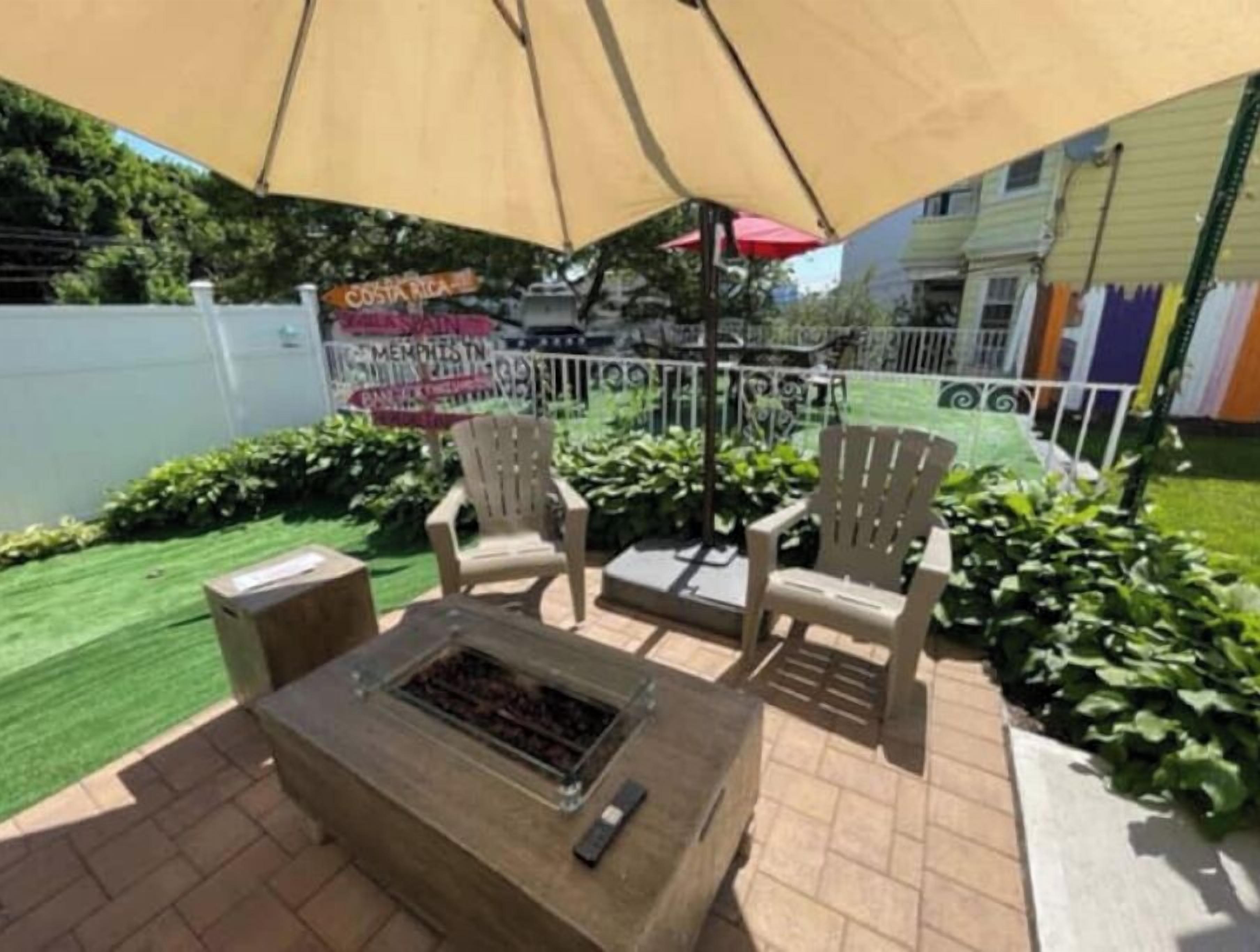 Une terrasse extérieure équipée d’un barbecue, de deux fauteuils Adirondack et d’un grand auvent.
