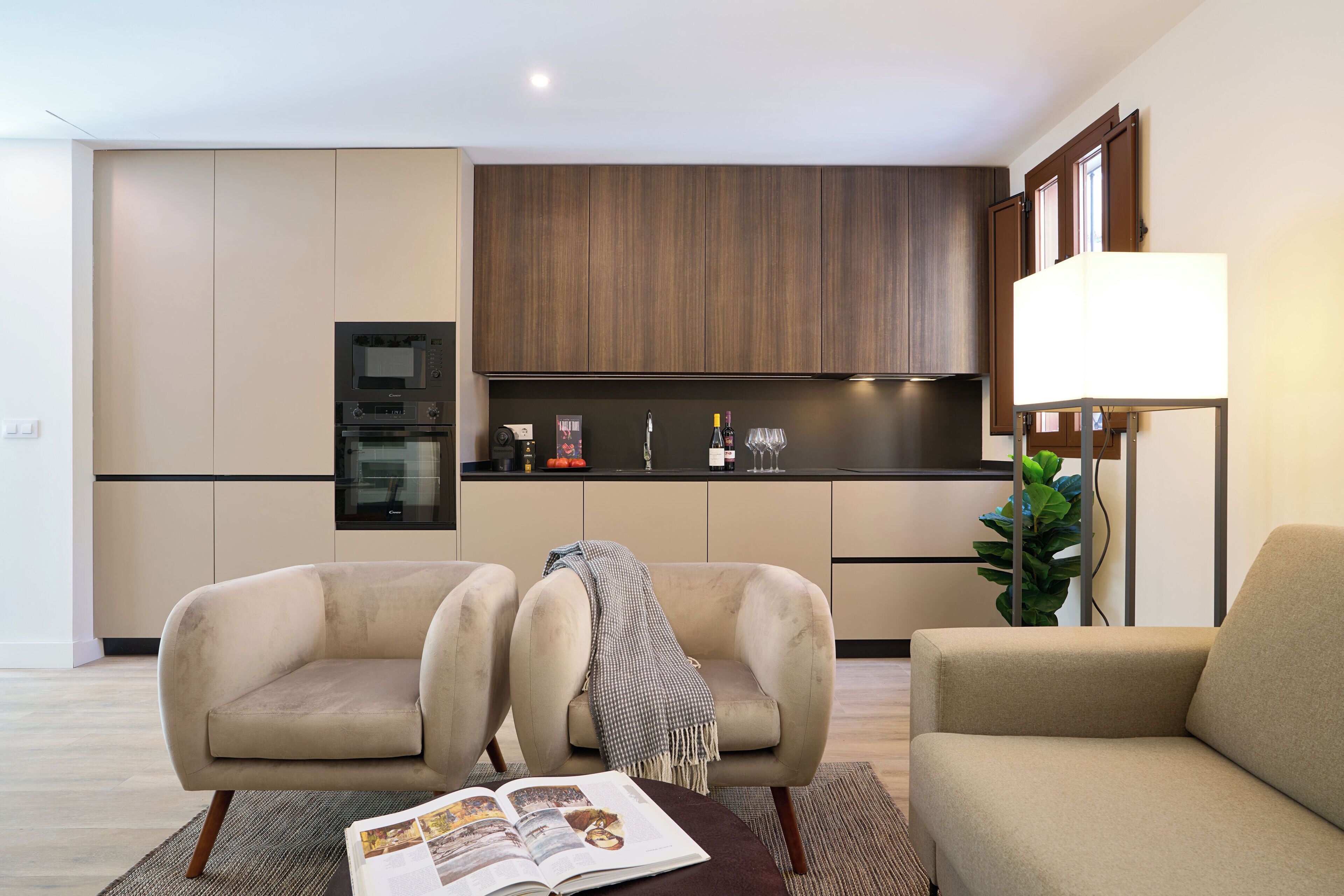 A modern living room with two sofas, a coffee table with a magazine, and a kitchen in the background.