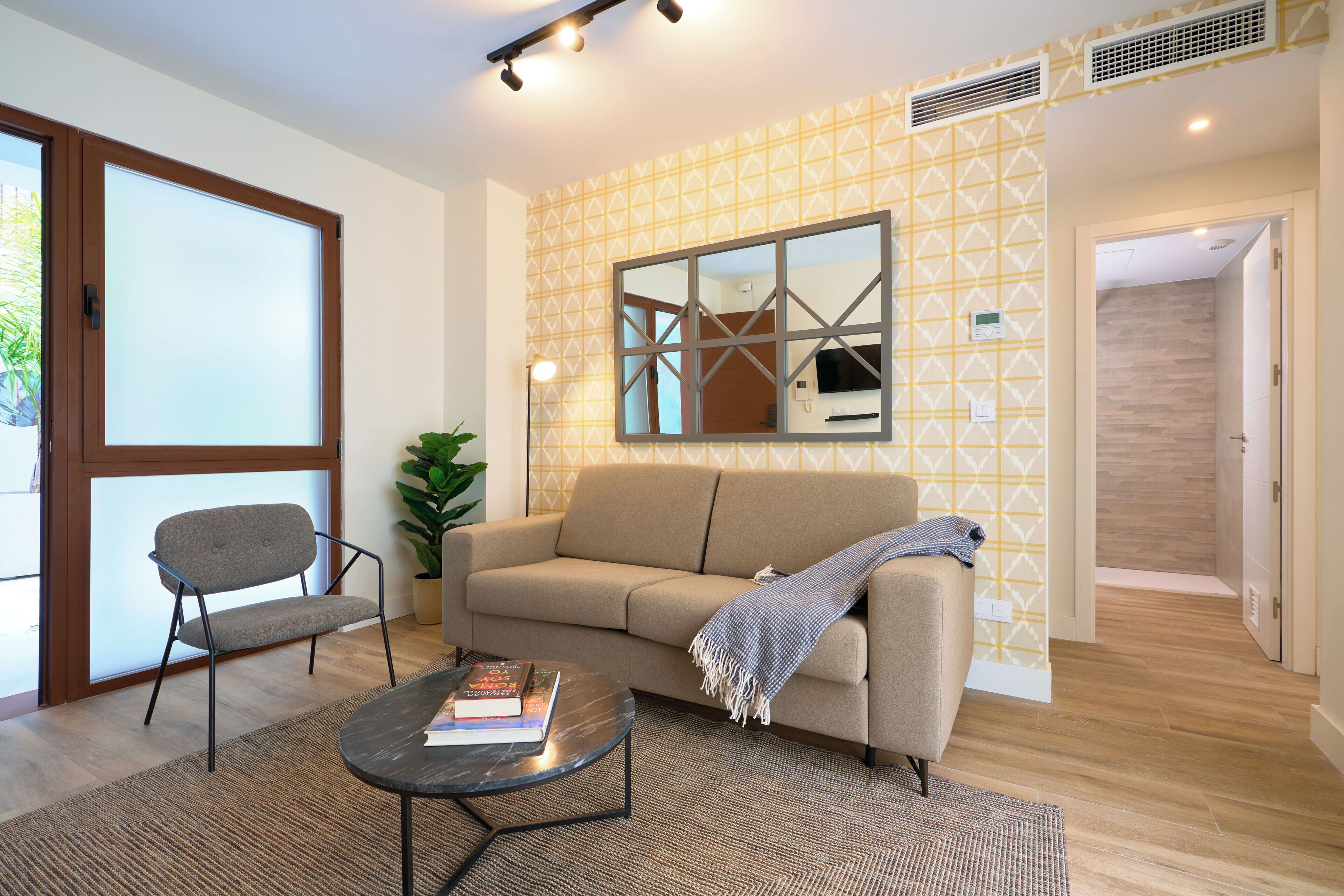 A modern living room with a sofa, a chair, a coffee table, and a large window.