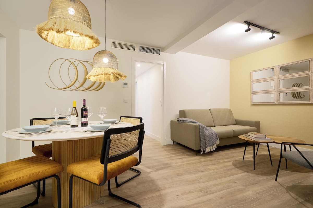 Un salon moderne avec un coin repas, comprenant une table ronde, des chaises et un canapé.