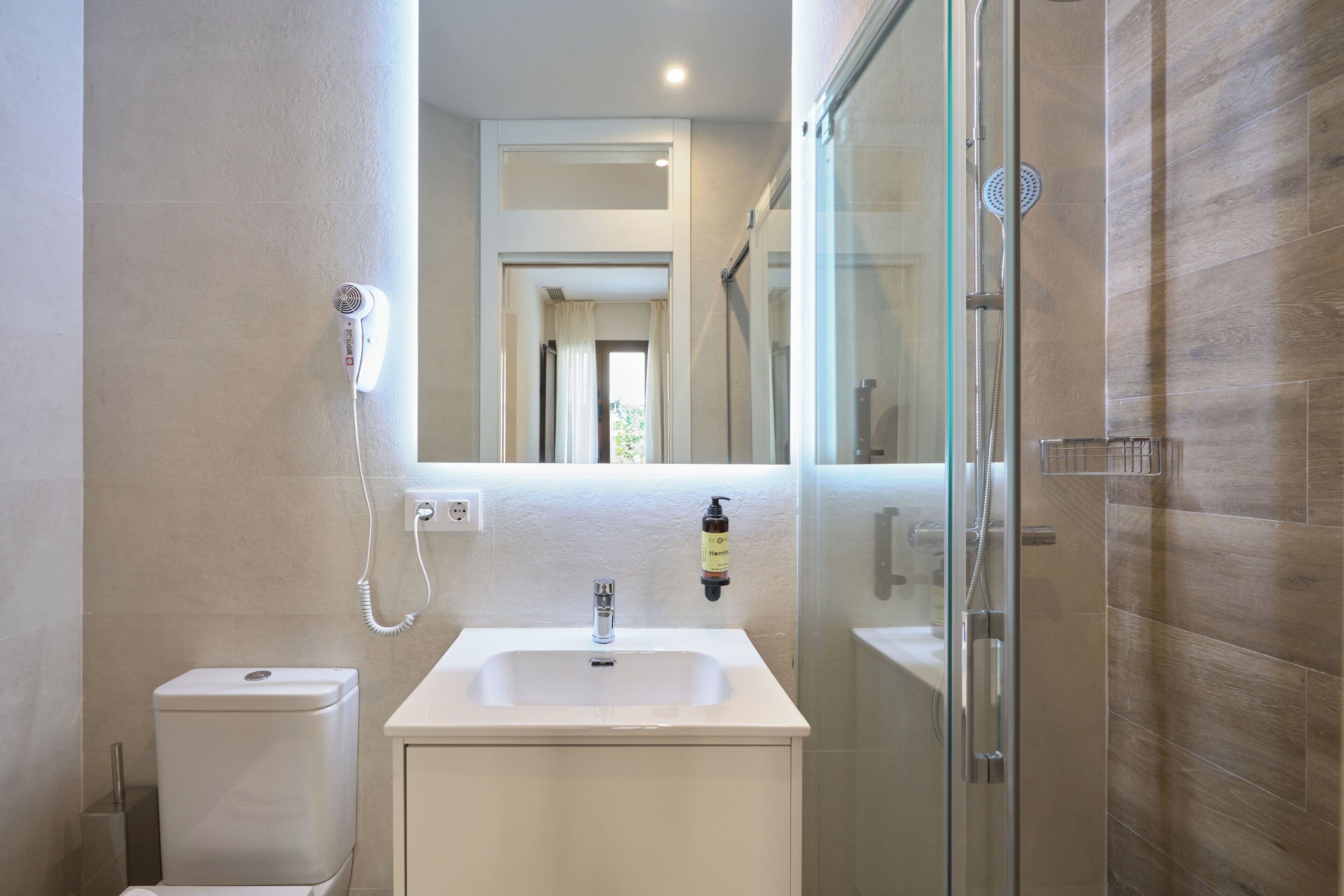 Un baño con lavamanos blanco, inodoro y cabina de ducha de vidrio.