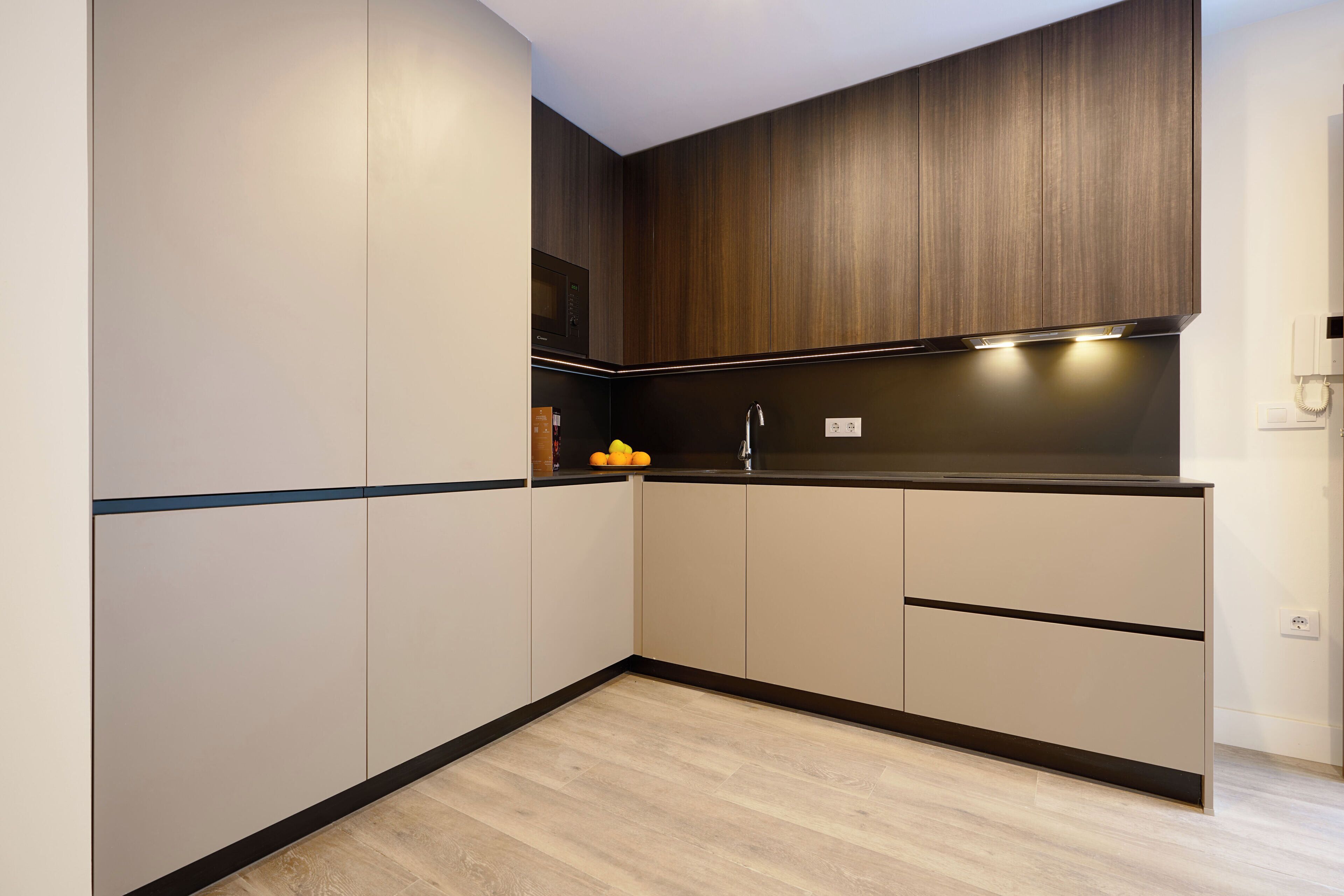 Una cucina moderna con mobili in legno, un piano di lavoro nero e un forno a microonde integrato.
