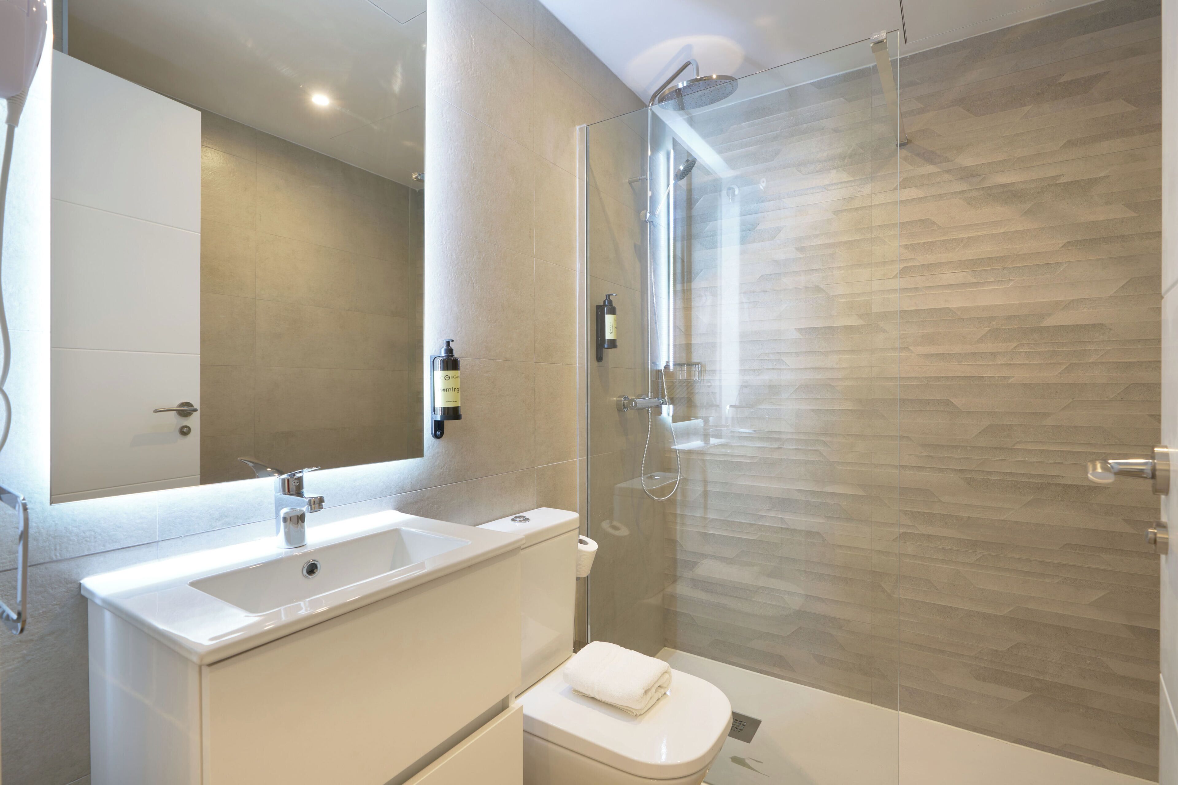 Un bagno moderno con box doccia in vetro, lavandino bianco e servizi igienici.