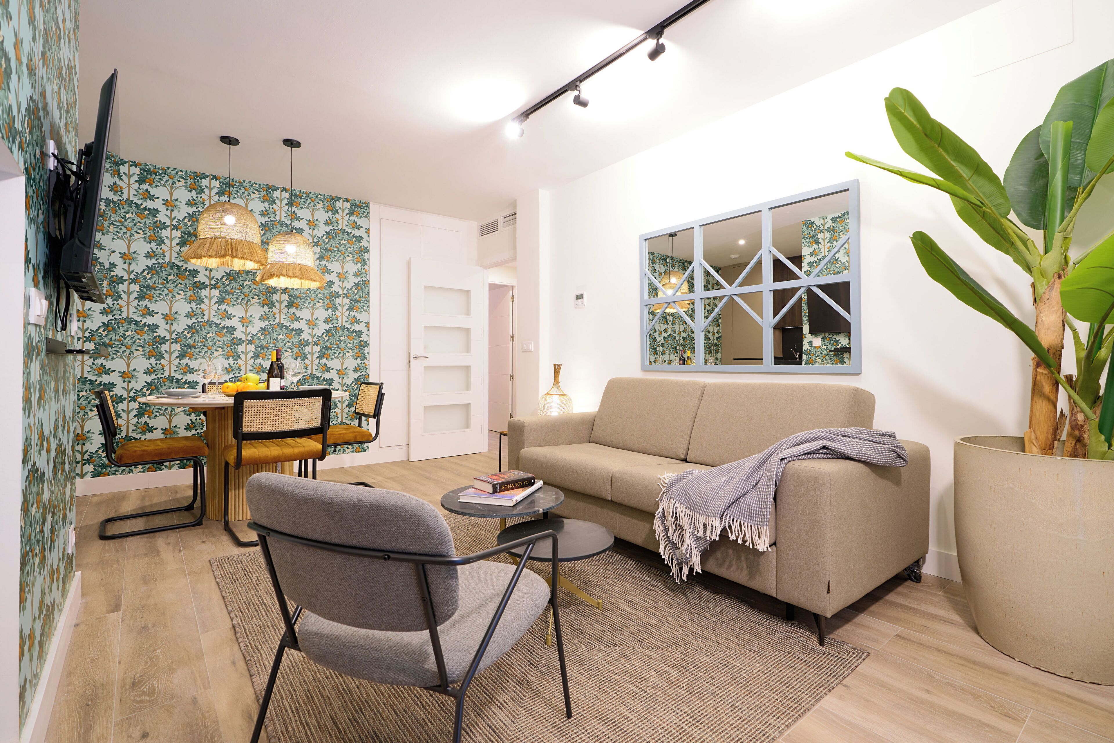 A modern living room with a sofa, armchair, dining table, and pendant lights.