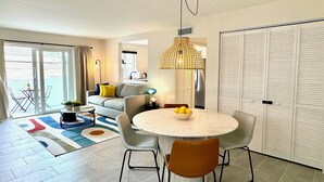 A modern living room with a round table, two chairs, a sofa, and a large window. - Casa Fifi Coral (Miami Beach)