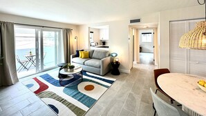 A modern living room with a sofa, coffee table, and a dining area with a table and chairs. - Casa Fifi Coral (Miami Beach)