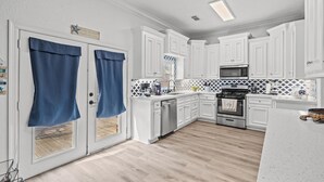 Une cuisine moderne avec des meubles blancs, un réfrigérateur en acier inoxydable et un four à micro-ondes.