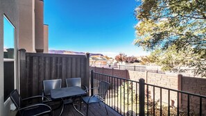 A balcony with a table and chairs, a wooden fence, and a view of a mountainous landscape. - Entrada at Moab 594 (Moab)