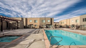 A pool area with a clear sky, a covered seating area, and a building with multiple windows. - Entrada at Moab 594 (Moab)