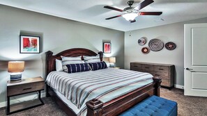 A bedroom with a wooden bed, two bedside tables with lamps, a ceiling fan, and decorative wall art. - Entrada at Moab 594 (Moab)