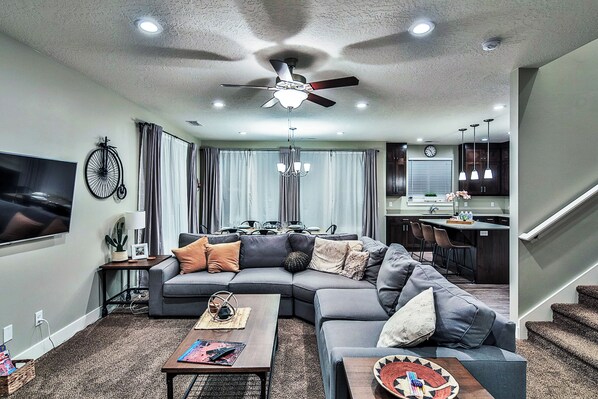 A modern living room with a sectional sofa, a coffee table, and a dining area with a kitchen in the background. - Entrada at Moab 594 (Moab)