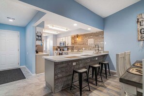 Een moderne keuken met een centraal eiland, barstoelen en een houten accentmuur.