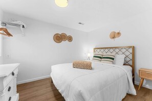 A bedroom with a bed, bedside table, and a dresser. - Enchanted Woods Retreat / Pools / Hot Tub (Branson)