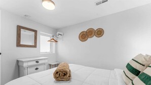A hotel room with a bed, a dresser, a mirror, and a window. - Enchanted Woods Retreat / Pools / Hot Tub (Branson)