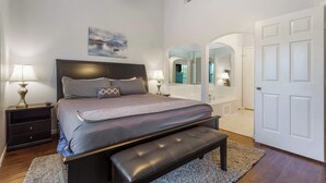 Ein Schlafzimmer mit Bett, Nachttischen, einer Bank, Deckenventilator und einem großen Spiegel.