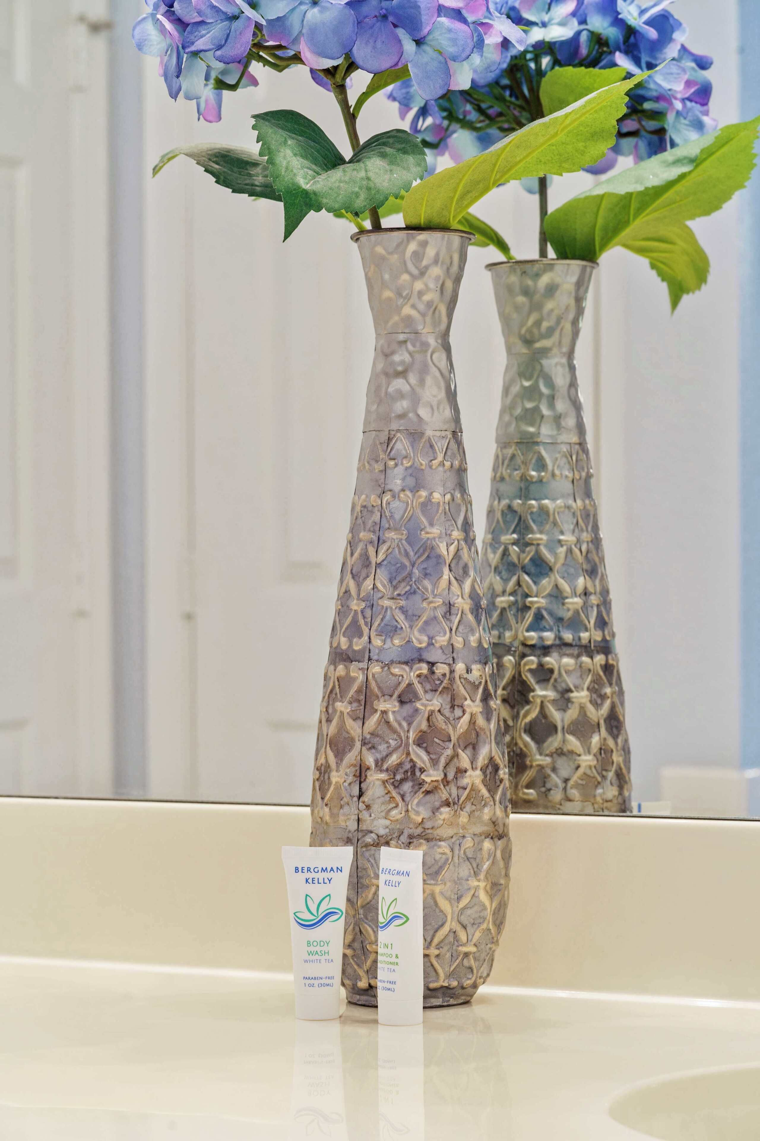 Twee versierde vazen met blauwe bloemen op een spiegelend oppervlak.